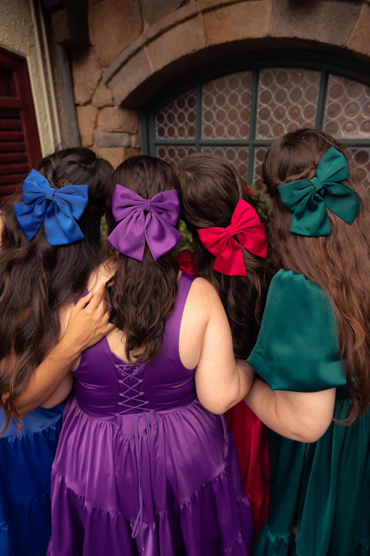 Women wearing gemstone collection hair bows in various shades with matching dresses