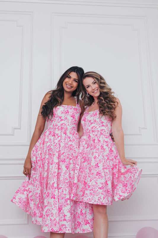 Two women pose in the Leading Lady Dress in Countryside Pink, showing the dress’s flattering twirl and fitted bodice.