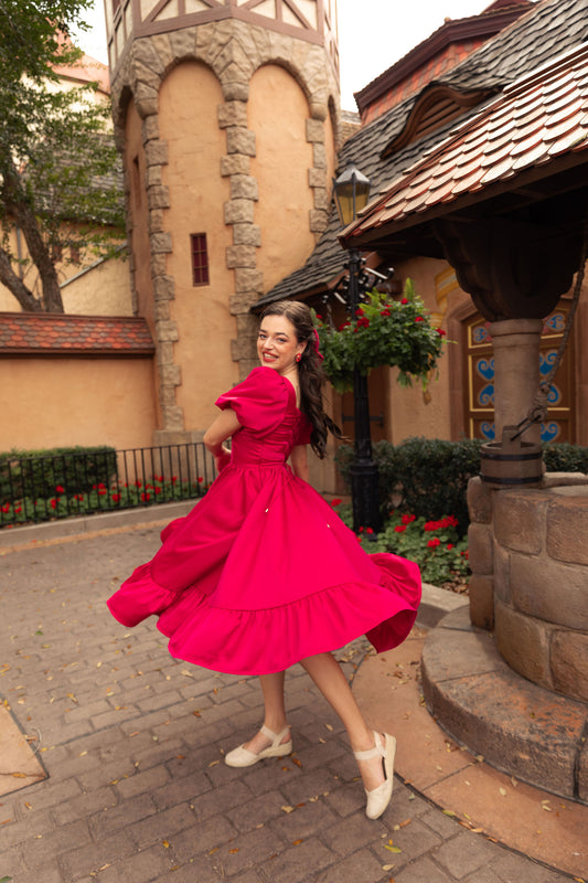 Novella dress in ruby red captured by a stone cottage