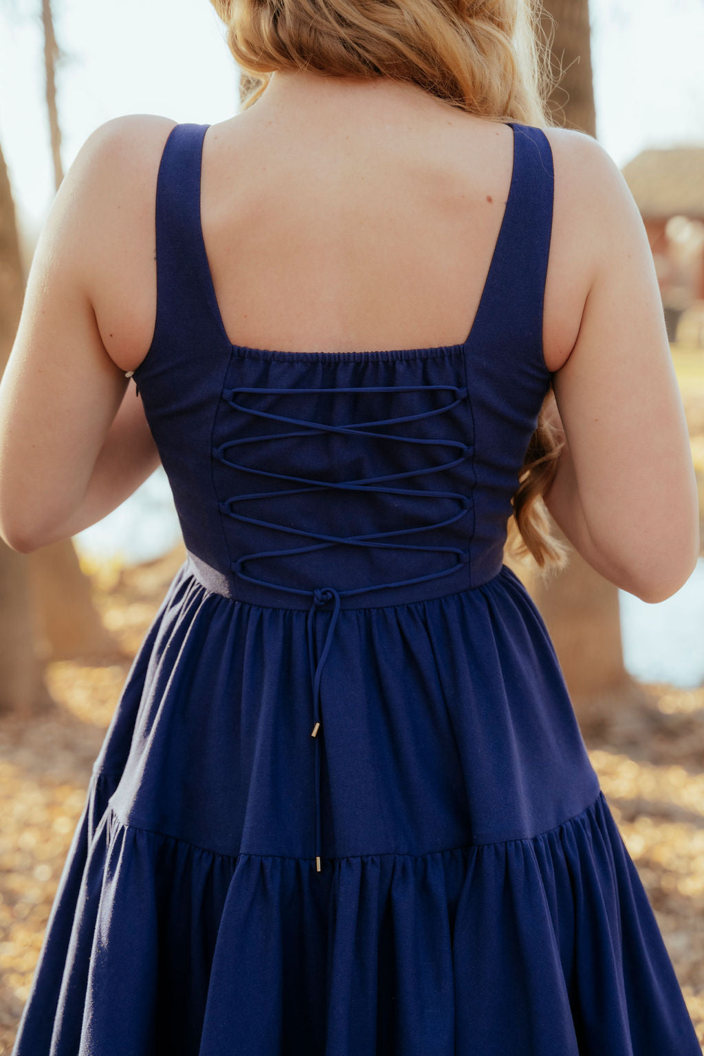 Navy blue dress with a unique back design worn by a person, blurred background