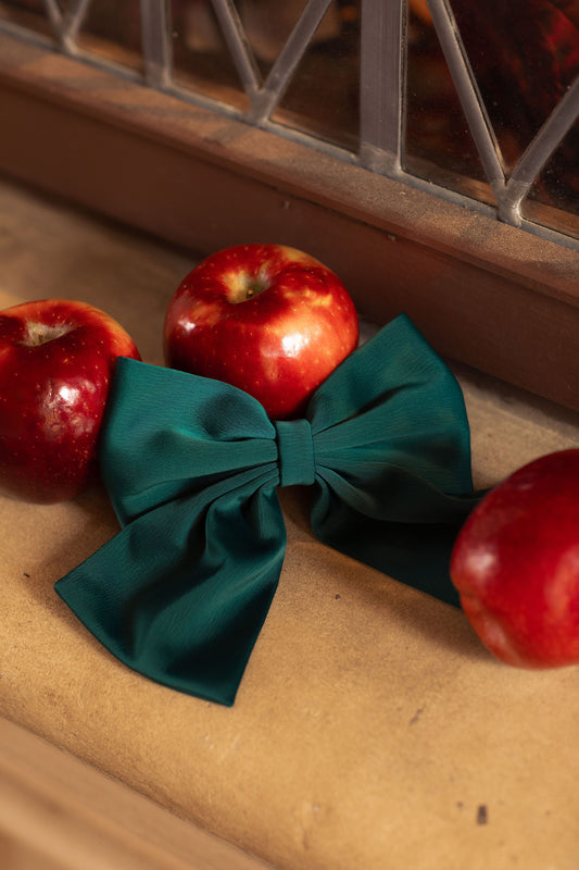 Tourmaline teal hair bow with ruby red apples on a stone ledge
